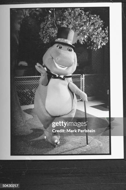Barney the dinosaur wearing top hat & bow tie, holding cane while performing song & dance on the TV show Barney And Friends.