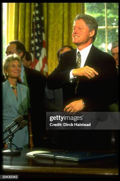 Pres. Clinton beaming during deficit reduction trust fund bill signing ceremony, as Rep. Jane Harman & various legislators look on.