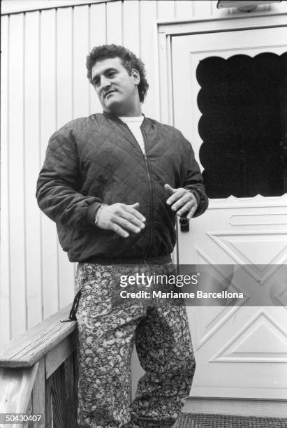 American auto repair shop owner Joey Buttafuoco, dressed in a jacket and a pair of pants printed with a cluttered skull design, stands on the steps...