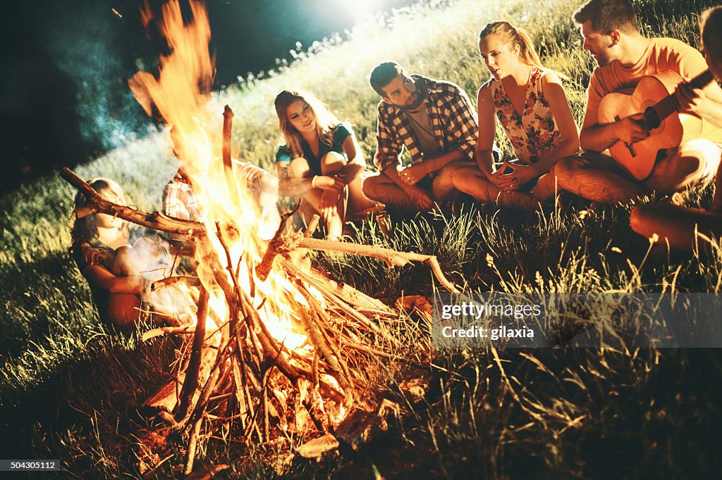 Campers relaxing next to bonfire.