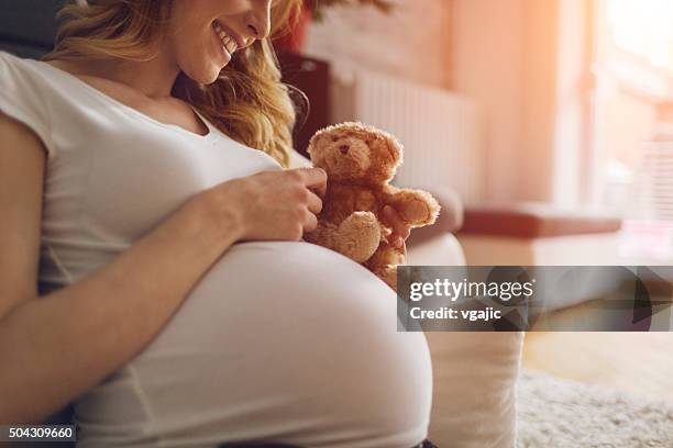 schwangere frau holding teddybär - hochschwanger stock-fotos und bilder
