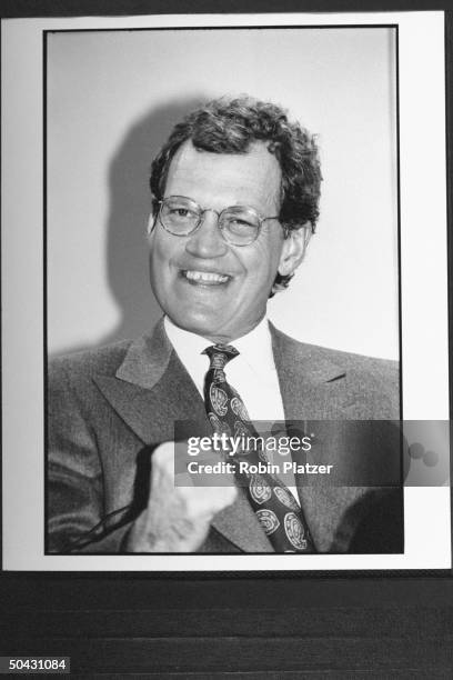 Talk show host David Letterman grinning zanily & proferring clenched fist, while announcing his move fr. NBC to CBS, at press conf.; his show will...