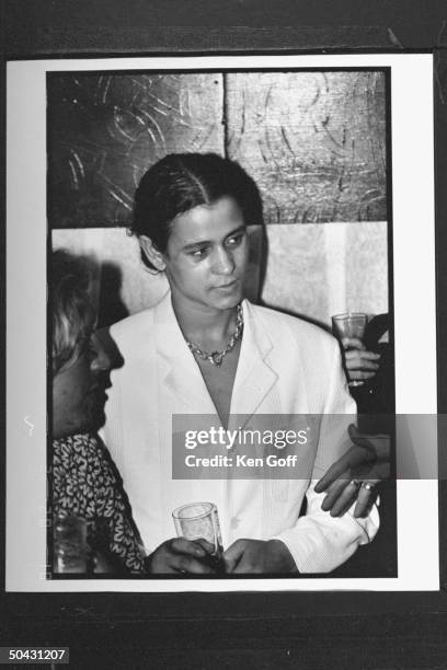 Actor Jaye Davidson clad in white suit, holding drink while listening to several patrons during Fur is a Drag Party at the Heaven club.