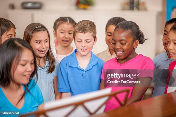 learning a new song around the piano - african childrens choir stockfoto's en -beelden