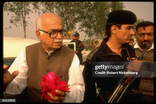 Hindu nationalist BJP member of Parliament/ex-Bharatiya Janata Party pres. L.K. Advani w. Roses fr. Supporters, flanked by bodyguard.