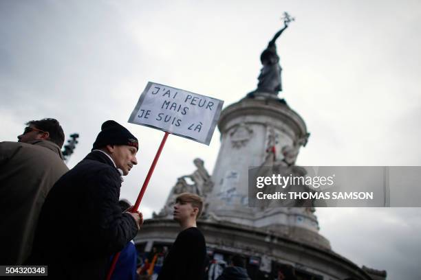 Man holding a placard reading "I am afraid but I am here" during a gathering on Place de la Republique on January 10, 2016 in Paris, as the city...