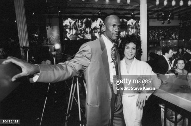 Chicago Bulls basketball star Michael Jordan posing w. Wife Juanita at bar at the opening of his restaurant.