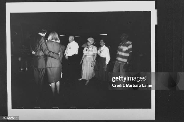 Sen. Bob Krueger w. His arm around his wife Kathleen Tobin Krueger, chatting w. Small group of people while campaigning at the Jefferson County...