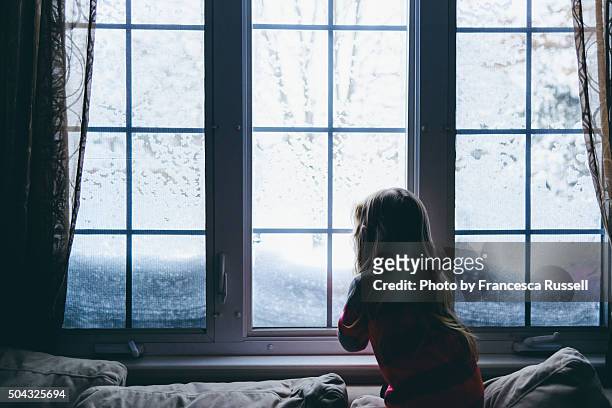 little girl looking out window at snow - bad weather on window stock pictures, royalty-free photos & images