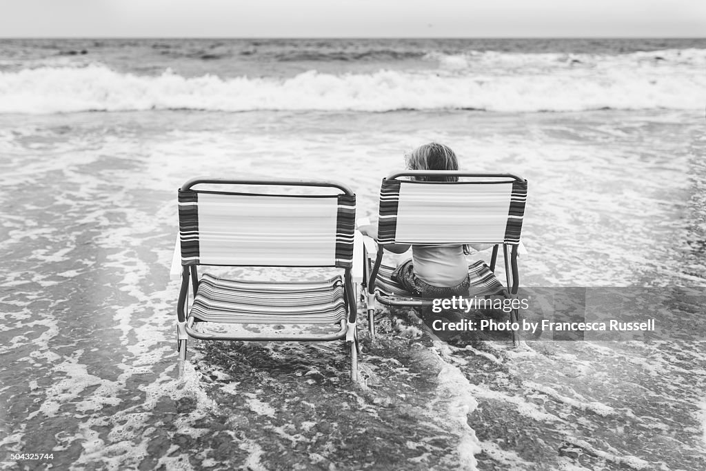 Girl sits on chair in ocean