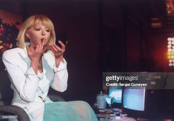 Tamara Maksimova, host of popular TV news show Public Opinion fixing her lipstick w. Aid of her compact mirror, prob. On set.