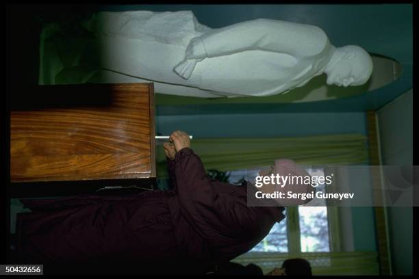 Woman inserting ballot in box, watched over by Lenin statue, voting in 1st democratic parliamentary elections at 55th district polls.