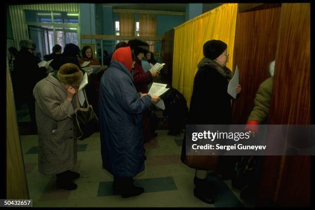 Voters waiting, scanning ballot choices, before casting ballots in 1st democratic parliamentary elections at 55th district polls.