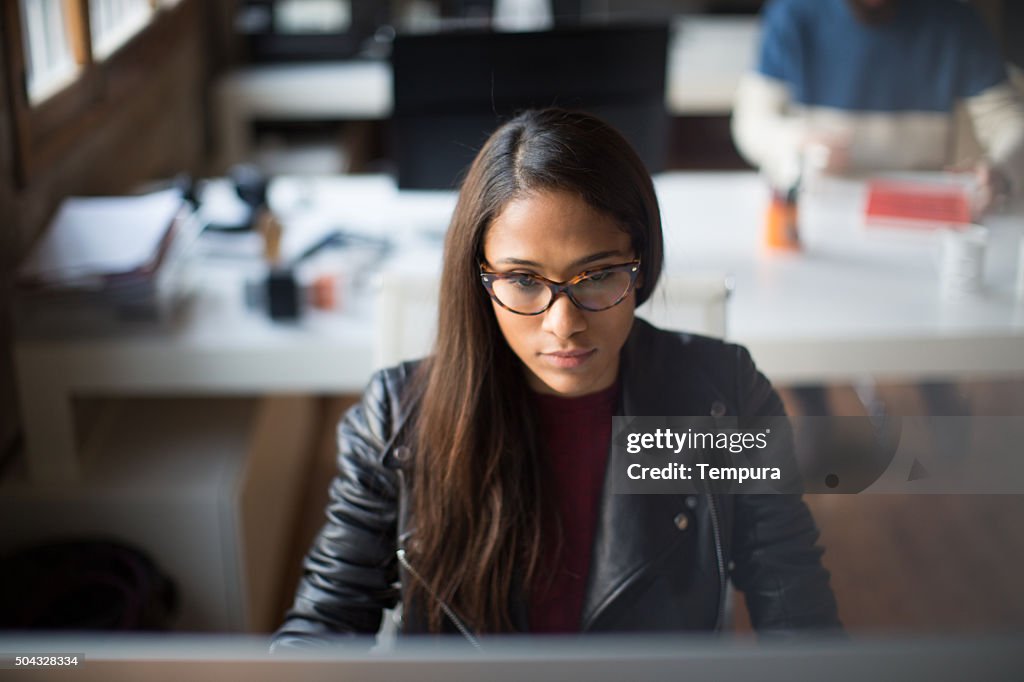 Bella donna è molto concentrato che lavora al computer.