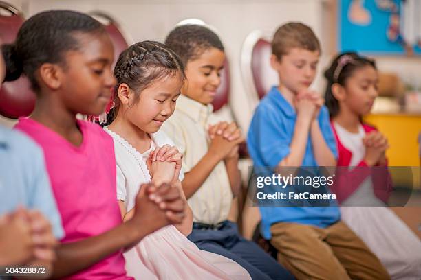 kinder beten zusammen - christentum stock-fotos und bilder