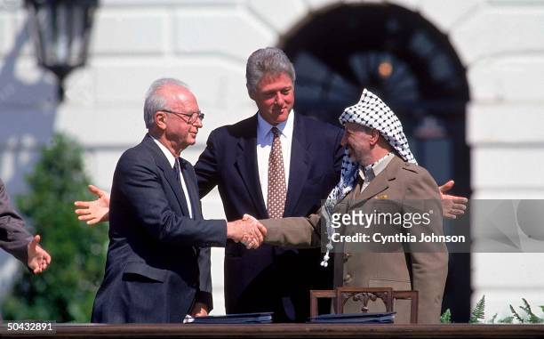 Pres. Clinton smiling as PLO chmn. Arafat & Israeli PM Rabin seal signing of Israel-PLO peace accord w. Historic handshake, at WH.