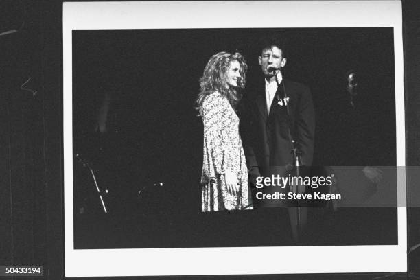 Actress Julia Roberts gazing adoringly at her husband, c/w crooner Lyle Lovett, as he sings into mike during concert at the Deer Creek Music Ctr., on...