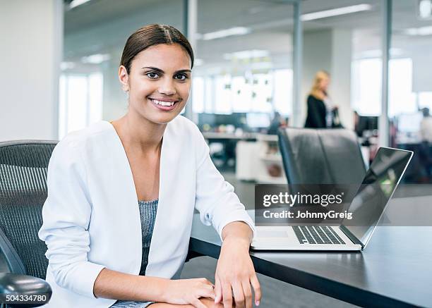 ethnic businesswoman at desk with laptop in modern office - australian woman stock pictures, royalty-free photos & images