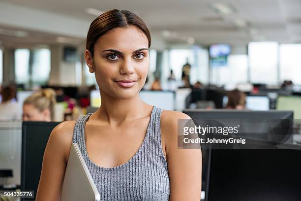 businesswoman with tablet smiling towards camera in modern office - aborigines stockfoto's en -beelden