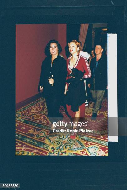 Actress/singer Madonna wearing low-cut maroon cotton adidas dress w. A side-slit & matching platform Puma sneakers, arriving w. Actress Rosie...