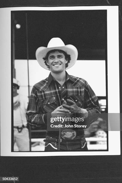 Actor Luke Perry wearing western garb, standing in rodeo ring during a break in the filming of the rodeo movie 8 Seconds.