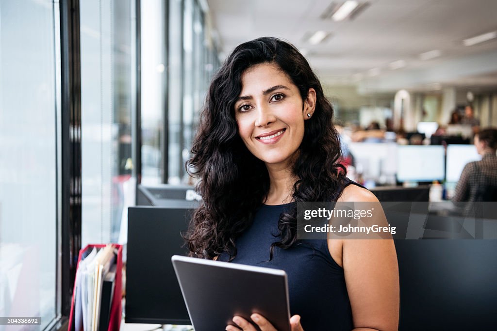 Middle Eastern businesswoman with tablet smiling towards camera