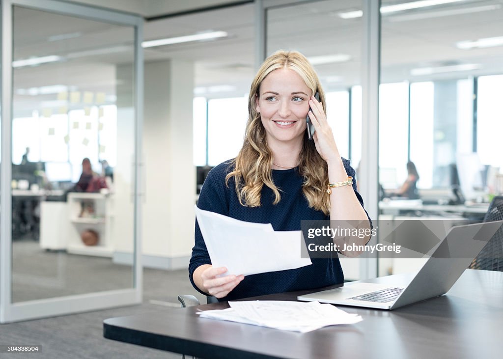 Businesswoman on phone in modern office, smiling