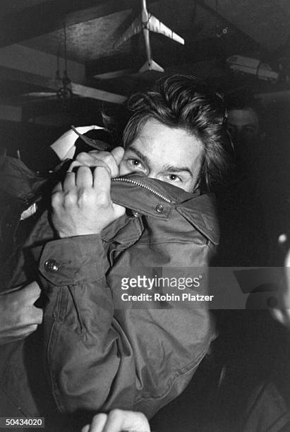 Actor River Phoenix covering his face w. His coat at an Artists Against Fur event.