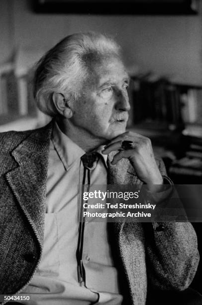 Pyschoanalyst Erik Erikson striking pensive chin-stroking stance, in his home study.