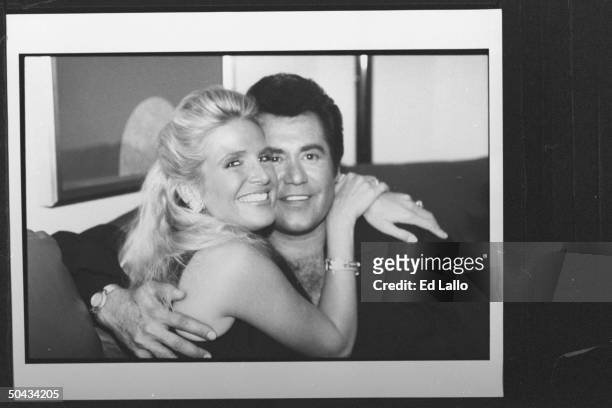 Singer Wayne Newton posing cheek-to-cheek w. His fiancee Kathleen McCrone in hotel room during his visit to perform at Rural Flood Relief concert.