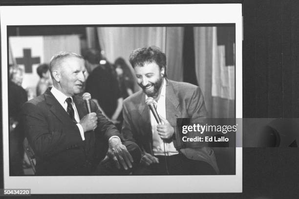 Russian comic Yakov Smirnoff chatting while interviewing politico Ross Perot as they sit backstage before performing at Rural Flood Flood Relief...