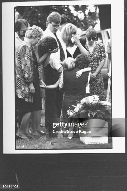 Yr-old Shervon Lakeberg being comforted & hugged by relatives while standing in front of the tiny flower-adorned coffin of her sister Amy, who died...