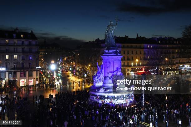 People gather on January 10, 2016 near the illuminated statue of the Republique at the Place de la Republique square during a remembrance rally...