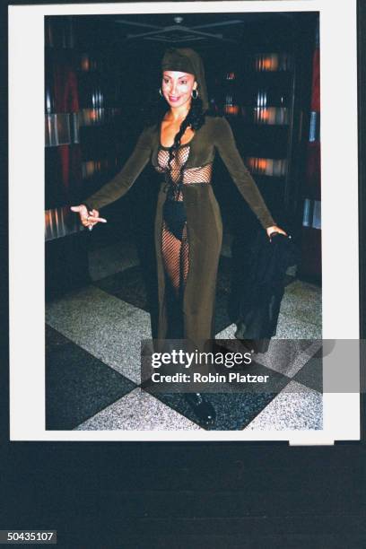 S Downtown Julie Brown pointing at her pelvic area as she shows off fishnet fashion designed by Betsey Johnson, revealing voluptious skin encased in...