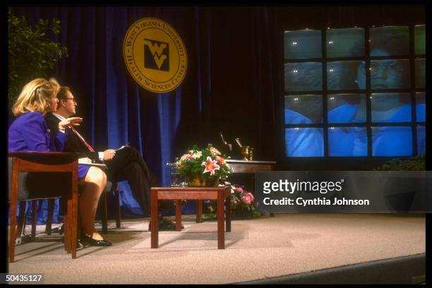 First Lady Hillary Rodham Clinton sitting onstage with Sen. Jay Rockefeller , watching video screen display during health care forum at West Virginia...