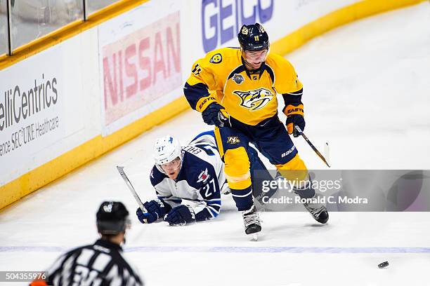 Cody Hodgson of the Nashville Predators skates with the puck as Nikolaj Ehlers of the Winnipeg Jets hits the ice during a NHL game at Bridgestone...