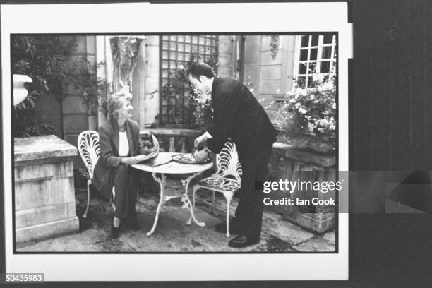 Author Joanna Trollope reading newspaper while waiter serves coffee at the English-Speaking Union in Mayfair.