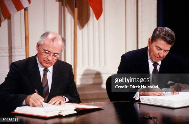 Soviet ldr. Mikhail Gorbachev & his summit host Pres. Reagan signing INF agreement in WH ceremony.