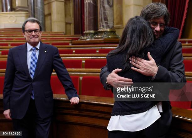 New elected President of the Catalan Government Carles Puigdemont hugs his wife past former President Artur Mas at the end of an investiture debate...