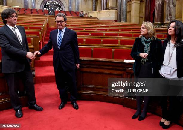 New elected President of the Catalan Government Carles Puigdemont shakes hands with former President Artur Mas next to their wives at the end of an...