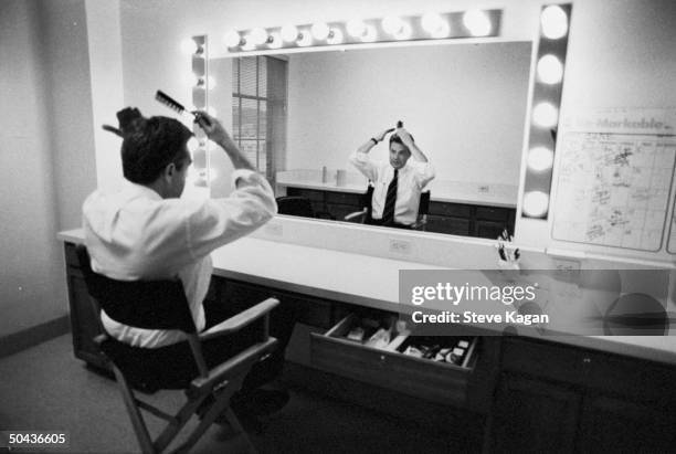 Ex-mayor/news anchorman/talk show host Jerry Springer brushing his hair while ditting in front of dressing rm. Mirror before taping The Jerry...