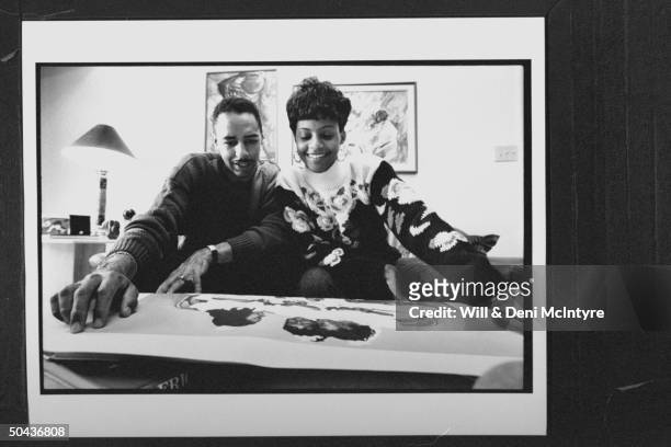 Black Entertainment TV's floating anchorman Ed Gordon w. His pregnant wife Karen looking over a ptg. They just purchased as they relax on couch at...
