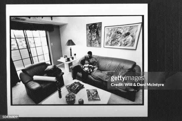 Black Entertainment TV's floating anchorman Ed Gordon snuggling w. His pregnant wife Karen while relaxing on leather couch in living rm. At home.