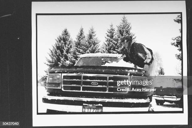 Olympic skier Picabo Street scraping a pile of snow off the windshield of her Ford pickup truck outside home.