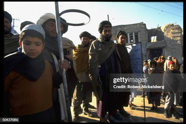 Men & boys assembled on street in city under control of Taliban, faction led by radical Islamic clerics winning civil war.