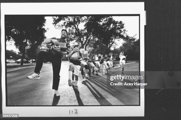 Apple Computer cofounder Steve Wozniak holding his Apple Macintosh Powerbook as he jubilantly leads a conga line of a dozen 6th & 7th graders, each...