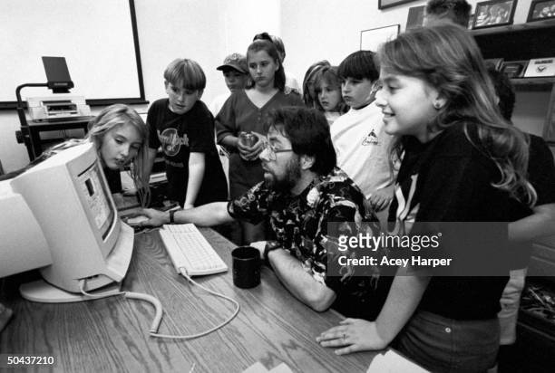 Apple Computer cofounder Steve Wozniak sitting in front of one of his Apple MacIntosh computers as a dozen 6th & 7th graders stand around him while...