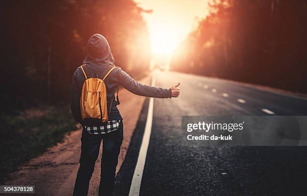 hitchhiking traveler trying to stop the car on road - hitchhiking stock pictures, royalty-free photos & images