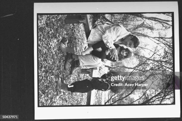 Holocaust survivor Zev Kedem sitting & holding daughter Katia on lap while telling story to son Adam who is standing nearby in a park; he was at...