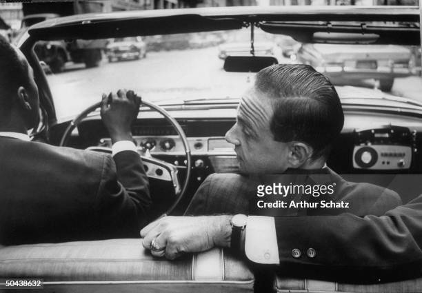 Jimmy McWhorter driving lawyer Roy Cohn and unident friend, all of whom are sitting in front seat of his 1961 Chevrolet Impala convertible, which...